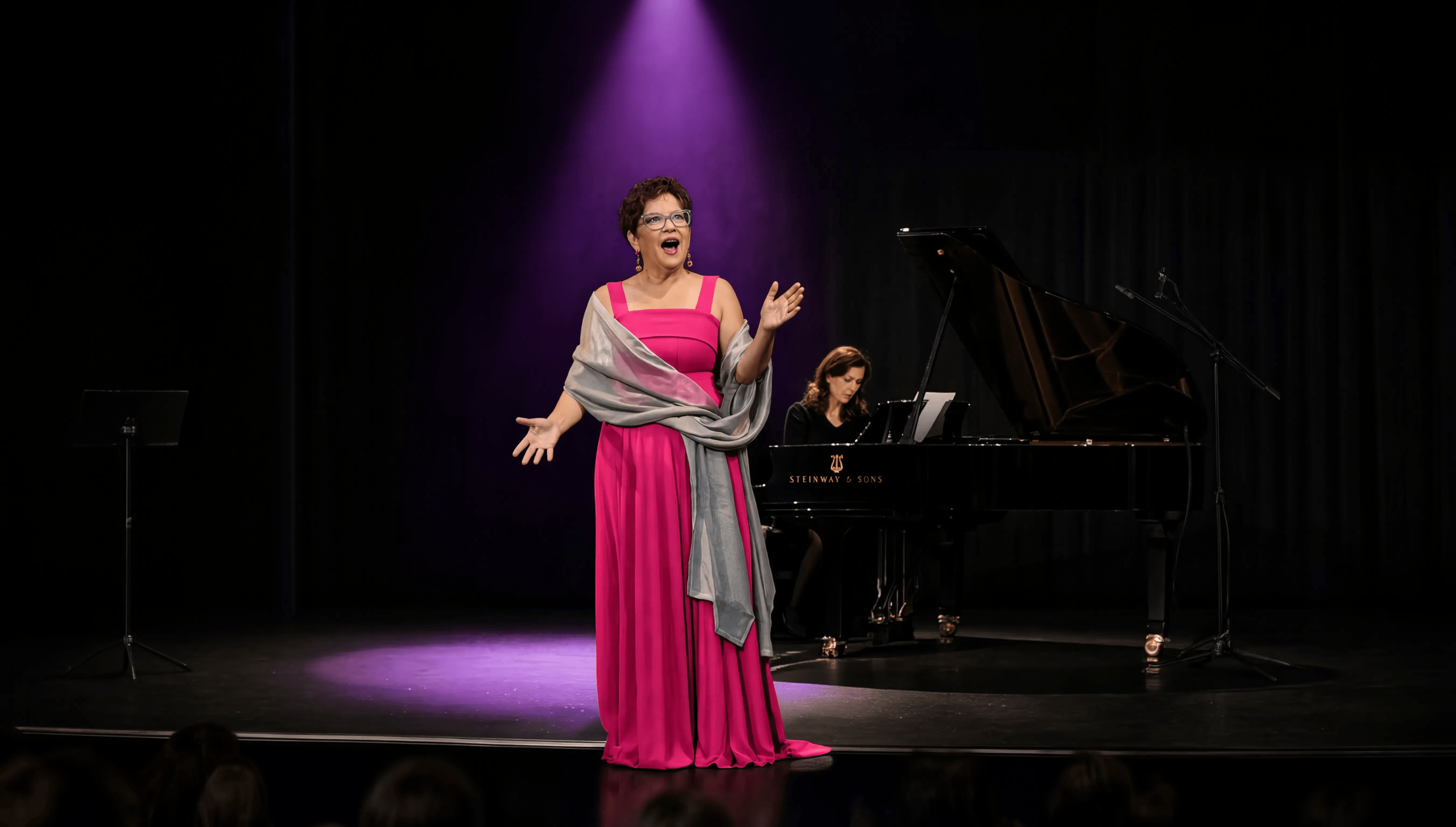 Mary Laymon performing on stage with piano accompaniment - Mary Laymon Voice Studio